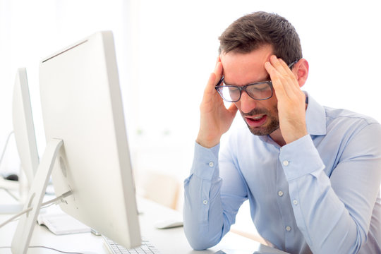 Young attractive man got a headache at the office