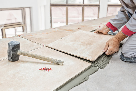 Handyman laying tile, trowel with mortar