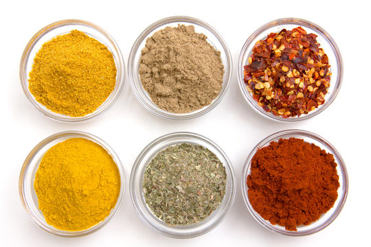 Bowls with spices viewed from above on white background