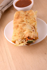 Burrito on white plate with sauce on wooden background