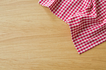 Checked tablecloth on wooden table. View from above