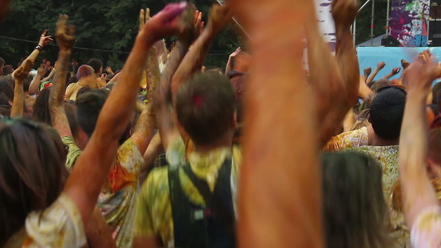 Crowd covered in colorful paint jumping to music at festival