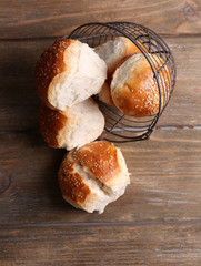 Tasty buns with sesame on color wooden background