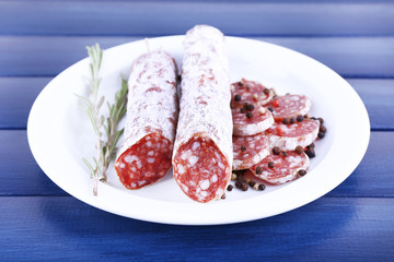 French salami on plate on dark blue wooden background