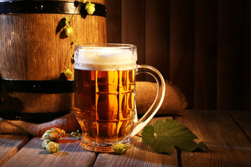 Beer barrel with beer glass on table on wooden background