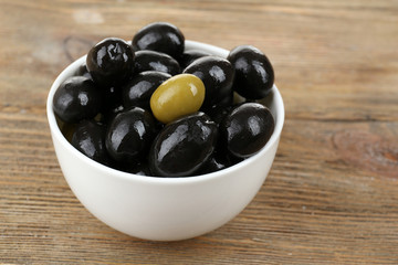 Individuality concept. Olive in bowl on wooden table