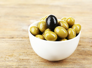 Individuality concept. Olive in bowl on wooden table