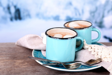 Cups of tasty hot cocoa, on wooden table, on light background