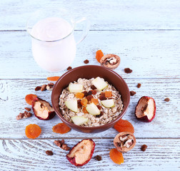 Bowl of oatmeal, walnuts, dried apricots, apples and yogurt