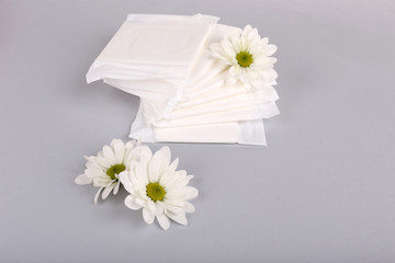 Sanitary pads and white flowers on light background