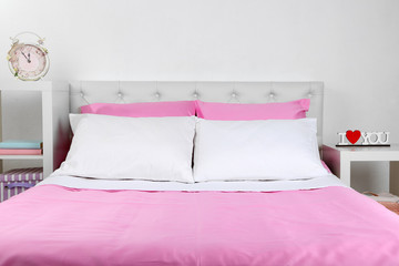 Bed in pink bed linen in room