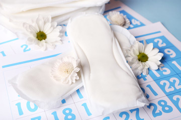 Obraz na płótnie Canvas Sanitary pads and white flowers on blue calendar background