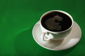 Cup of coffee on green background