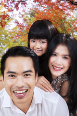 Fototapeta premium Attractive family smiling under autumn tree