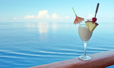 A tropical drink on a cruise ship rail with ocean in the backgro - 72175920