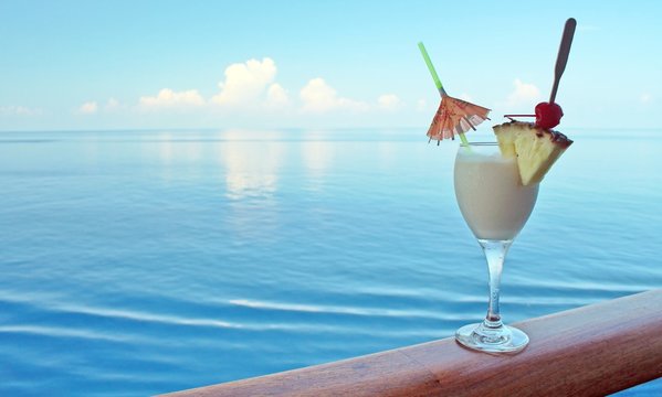 A tropical drink on a cruise ship rail with ocean in the backgro