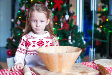 Adorable little girl baking gingerbread cookies for Christmas at