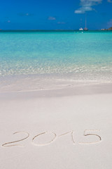 2015 written on tropical beach white sand with xmas hat
