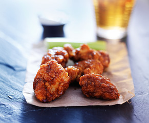 beer and spicy boneless chicken wings on slate