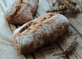 Homemade bread rolls with wheat ears on a wooden table boards