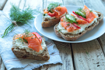 Plate with sandwiches with salmon on a wooden table boards