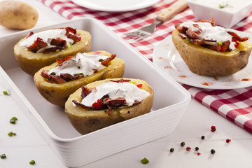 Baked potatoes stuffed with bacon served with dill sauce