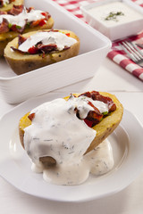 Baked potatoes stuffed with bacon served with dill sauce