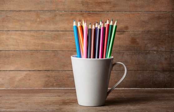Color pencil in cup on a wooden background