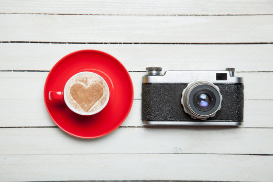 Retro camera and cup of coffee on wooden table.