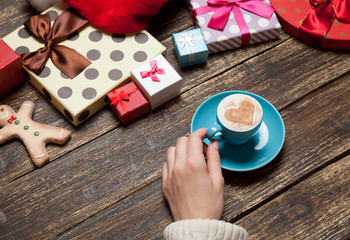 Female holding cup of coffee on wooden table near christmas gift