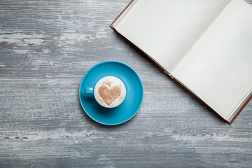 Book and cup of coffee on wooden table.