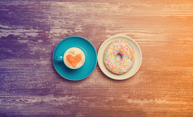 Cup of coffee and donut on a table.