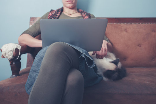 Woman working on laptop with cat