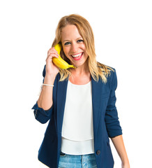 Blonde girl with banana as phone over white background