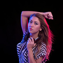 Young sexy deejay woman against black background with strobe lig