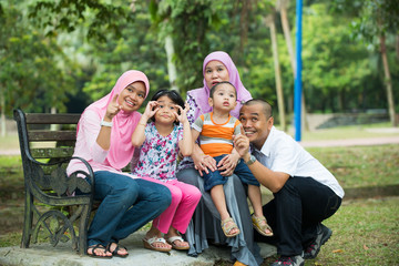 malay muslim family having fun playing in the park