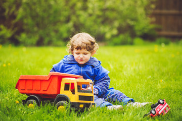 A child plays a toy car on the grass in the park.