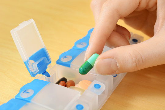 Frau nimmt Pille und Tablette aus Pillendose