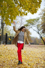 Young woman in fashion coat walking in autumn park