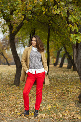 Young woman in fashion coat walking in autumn park