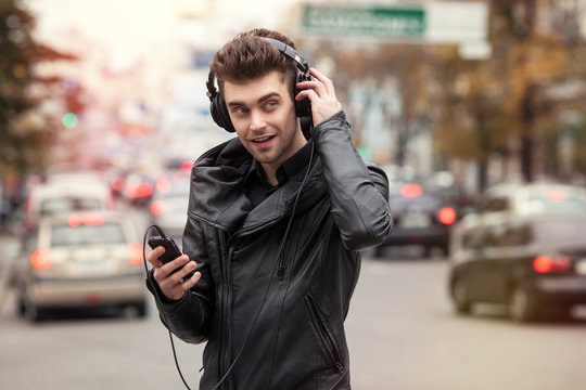 man in headphones on the street. Standing with phone in hand
