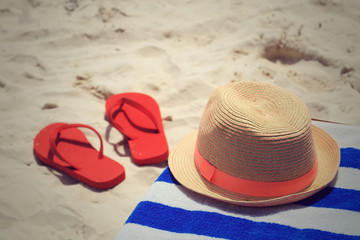 Straw hat, towel and flip flops on tropical beach