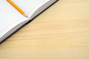 Diary and pencil on wooden table with free text space.