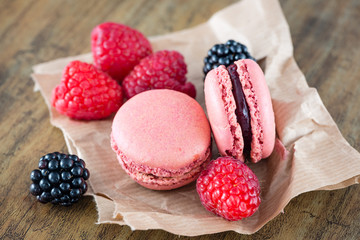 Macaroons and berry fruits on wooden background