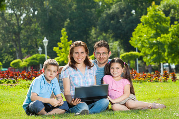 Fototapeta na wymiar Happy Family using laptop lying on grass