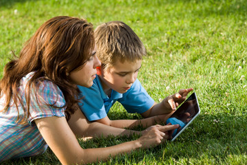 Happy Family using laptop lying on grass