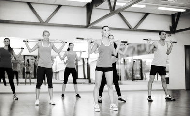 group of smiling people working out with barbells