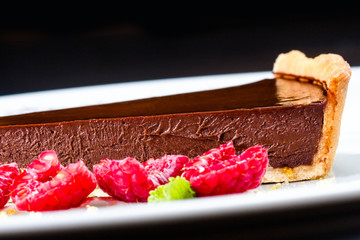 Piece of Sweet chocolate cake with fresh raspberries close up. .