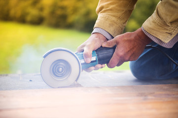 Carpenter grinding wooden planks