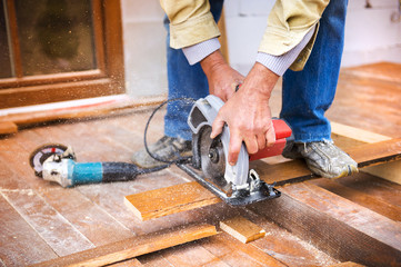 Carpenter grinding wooden planks